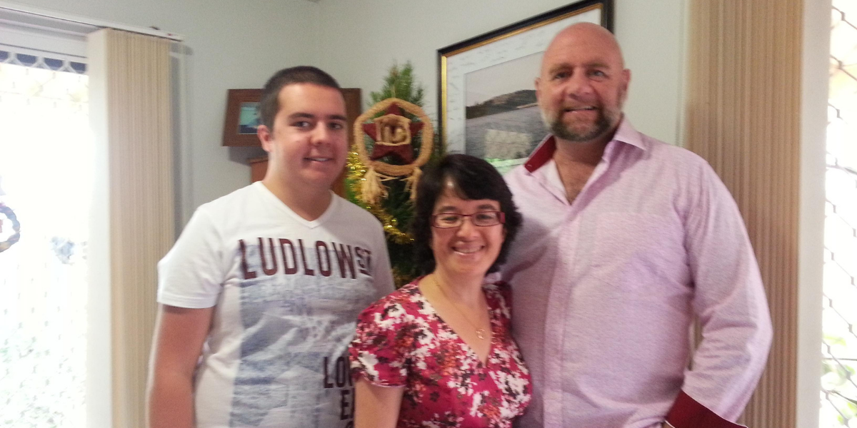 Simon with his wife and son in front of a Christmas tree in the living room.