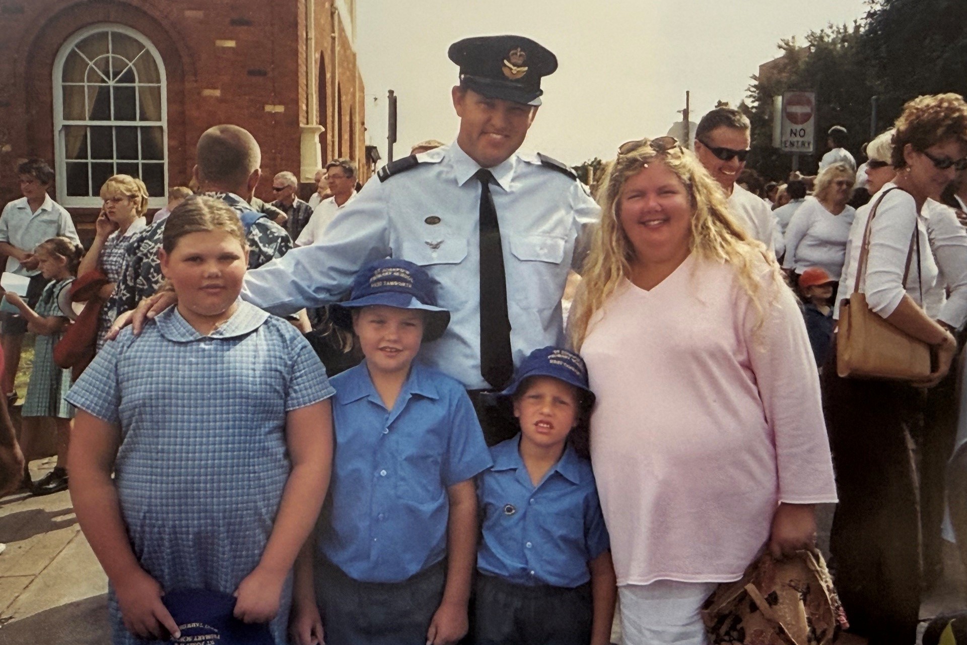 A dated photo of a family of five - Dad, mum and three children dressed in school uniform, with the Dad in his Air Force uniform