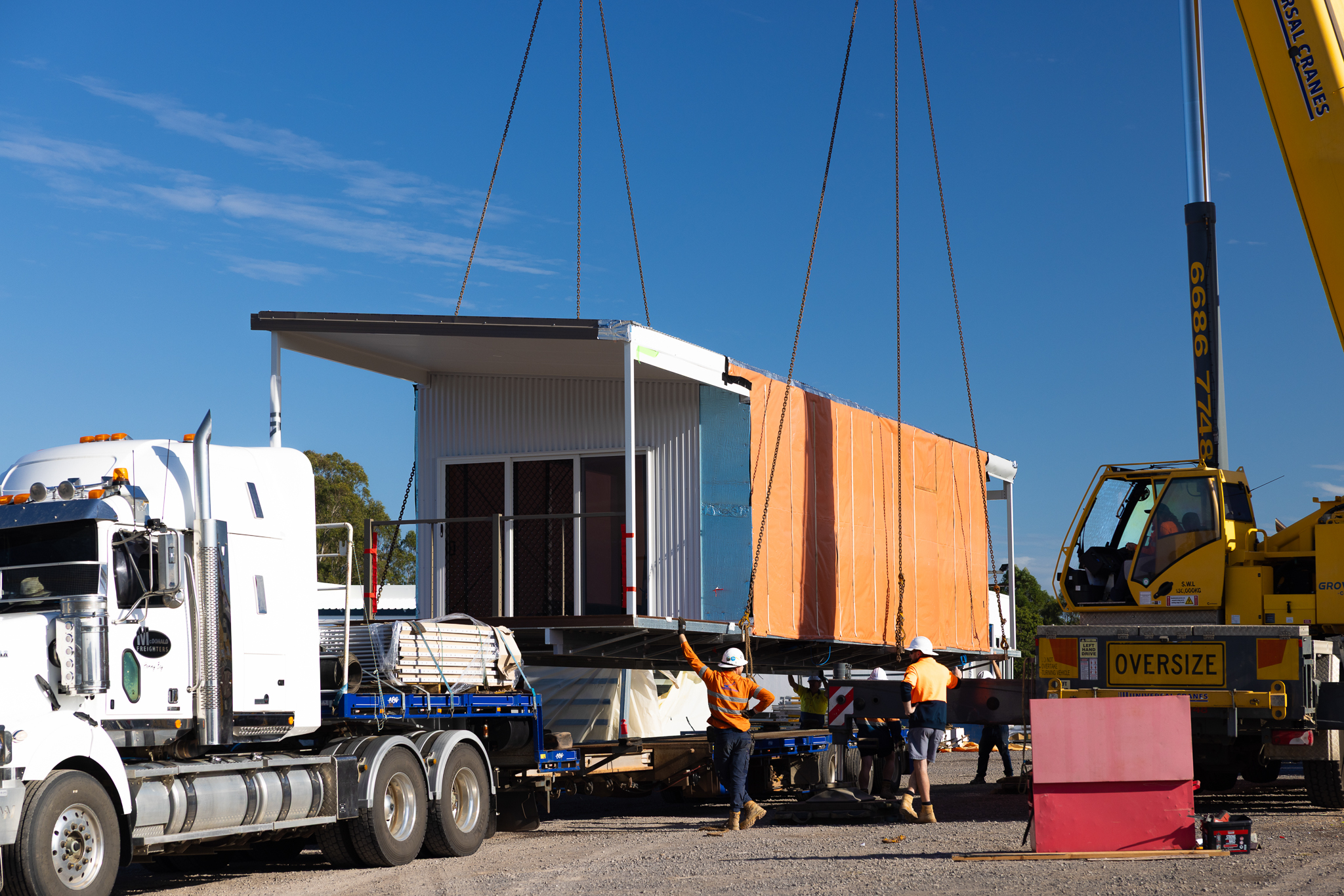 House being lowered by crane onto the trailer of a truck