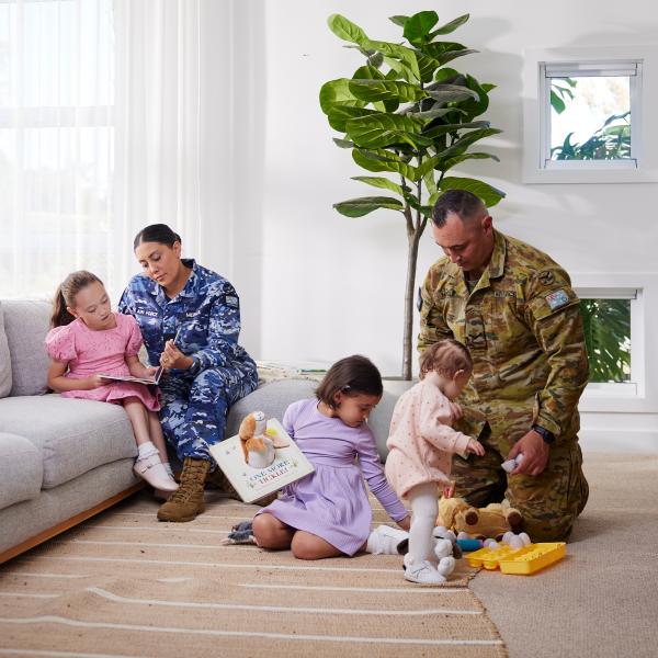 A Defence couple (Air Force and Army) play with their young children in the lounge room.