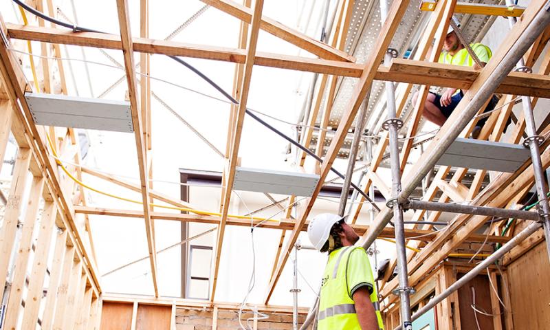 Two workers with safety vests and hard hats on a construction site. 